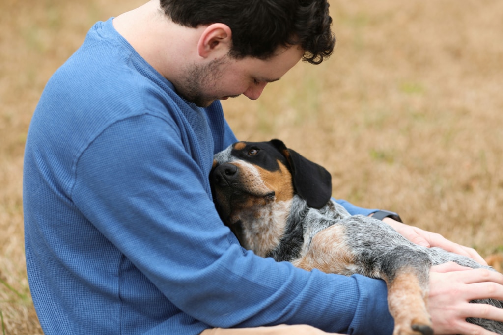 Dog in owner’s arms after dental problems were detected, supported by Oven-Baked Tradition for dental care for dogs